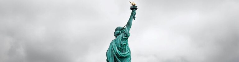 Bild der Freiheitsstatue in New York mit grauen Wolken im Hintergrund.